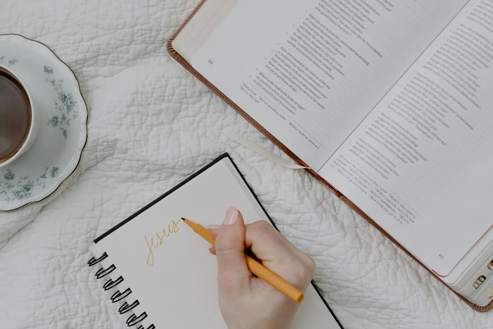 An open Bible beside a journal and a cup of coffee