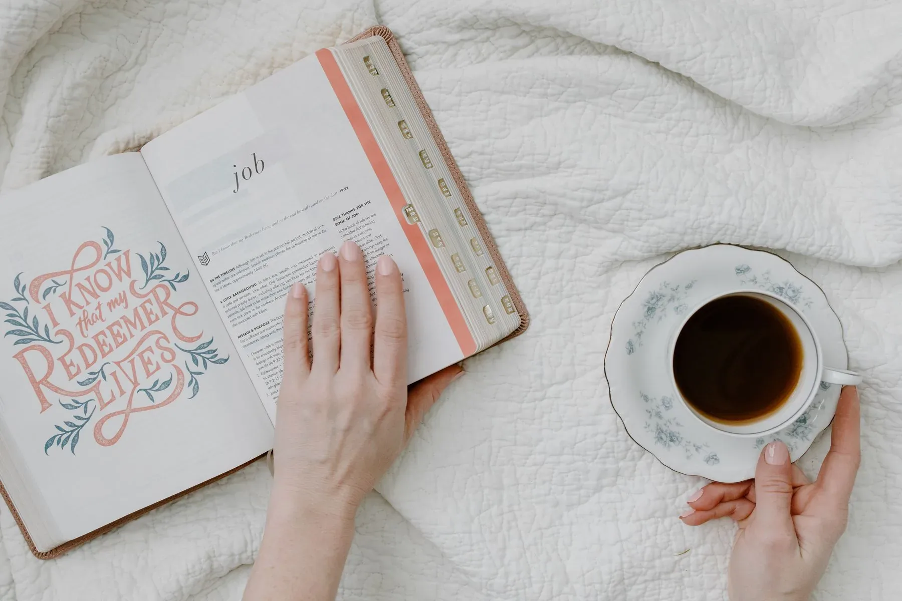 Hands resting beside an open Bible and a cup of coffee